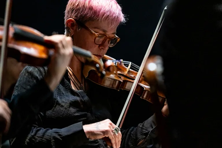 a girl with pink pixie cut playing a violin